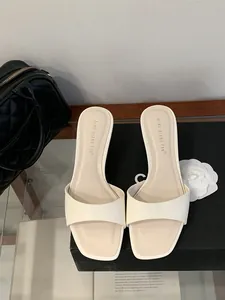 Primo piano di sandali minimalisti color crema a punta quadrata su una scatola elegante