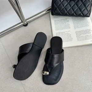 Gedetailleerd overzicht van zwarte platte teenslippers met metalen kraal en leer