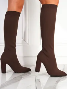 Detailed side view of brown knitted stretch boots with chunky high heel and pointed toe.