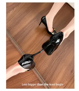 Detailed view of black patent leather pointed toe stiletto heels with mirror reflection