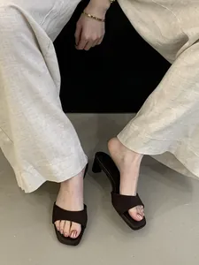 Dettaglio di sabot marroni a punta quadrata e tacco largo con pantaloni in lino