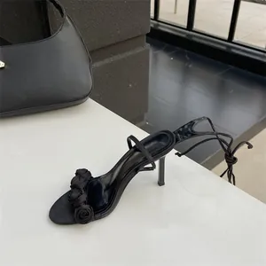 Detailansicht schwarzer High-Heel-Sandalen mit Schnürung und Rosen-Applikationen