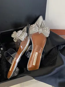 Nahaufnahme eleganter Pantoletten mit glitzernder Strassschleife und Kristallabsatz