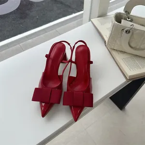 Close-up of red pointed-toe slingback heels featuring a decorative fabric bow