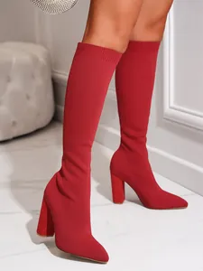 Detail view of red knitted elastic knee-high boots featuring a stylish chunky heel