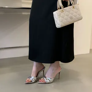 Detailaufnahme von silbernen Stilettos mit spitzer Zehenpartie und Knotendetail