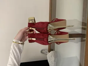 Close-up detail of burgundy suede stiletto high heels with gold ankle strap and back zipper