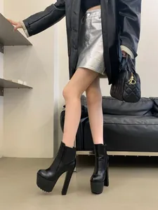 Model wearing 16cm black platform ankle boots with thick high heels for height boost
