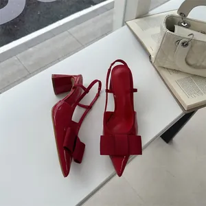 Detailed view of elegant red patent leather slingback high heels with oversized bow detail