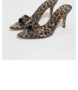 Dettaglio ravvicinato di eleganti sabot leopardati con tacco alto e un moderno design a punta quadra