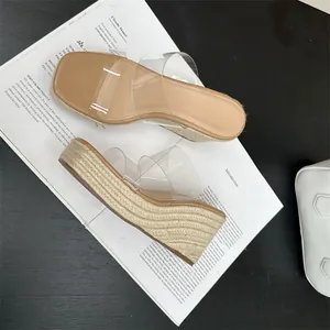 Close-up detail of women's fashionable square-toe wedge slippers with clear PVC straps.