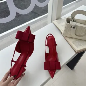 Elegant red patent leather slingback heels featuring a large bow and sturdy chunky heel
