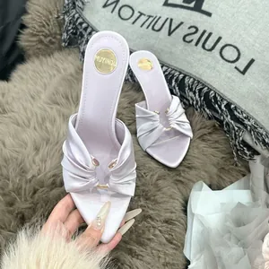 Detailansicht der fliederfarbenen Satin-Sandalette mit Goldring und Spitze.