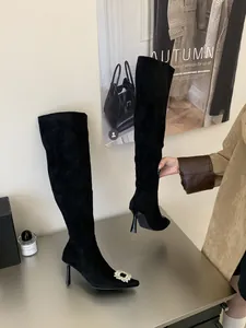 Detail of black over-the-knee boots featuring a sparkling rhinestone square buckle