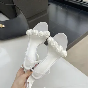 Nahaufnahme weißer High-Heel-Sandalen mit zarten Seidenrosen-Blumen-Zhenriemen