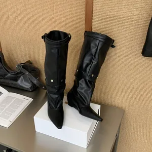 Macro view of black pointed-toe rider boots with metallic studs and cuffed design