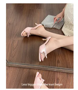 Close-up of pink kitten heel mules with bow detail and crocodile texture on wooden floor