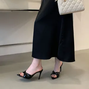 Detailaufnahme eleganter schwarzer spitzer High-Heel-Mules mit Knotendesign