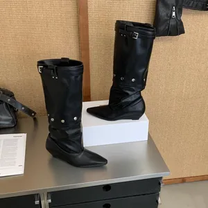 Side view of black pointed-toe knight boots featuring silver stud and buckle details on wedge heel