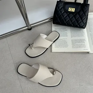 Elegante gebroken witte platte teenslippers voor dames met een uniek zilverkleurig metalen detail