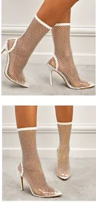 Detail of white mesh stiletto boots with elegant fishnet pattern and pointed toe.