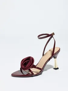 Detailed side view of elegant burgundy satin high heel sandal with oversized rose