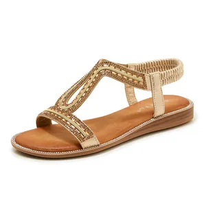 Primo piano di sandali boho dorati con decorazioni in strass e cinturino elastico.
