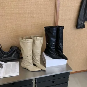 Macro view of stylish pointed-toe wedge boots with buckle detail on a modern display shelf