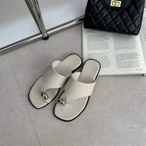 Detailweergave van crème vintage platte teenslippers met een metalen teenringaccent