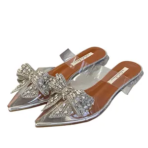 Detailansicht der spitzen Mules mit glitzernder Strassschleife und transparentem PVC.