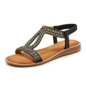 Dettaglio ravvicinato di sandali flat boho con cinturini in strass ed elastico.