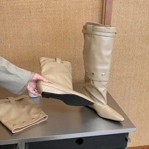 Detailed macro view of beige pointed-toe wedge boots with a unique trouser leg design