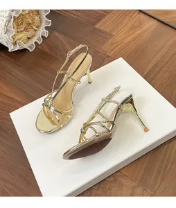 Elegant metallic gold stiletto sandals with strappy knot detail on a white pedestal