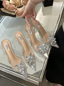 Gros plan de talons argentés à fleurs en cristal et brides transparentes.