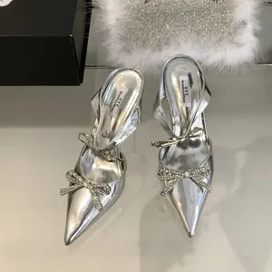 Detail view of silver pointed-toe high heels with sparkling rhinestone bow and slingback strap