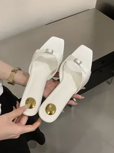 Close-up of white square toe mules with elegant rhinestone buckle detail