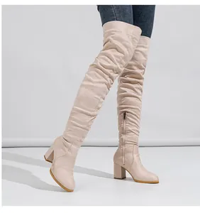 Detail view of cream suede over-the-knee boots with chunky high heels and side zipper.