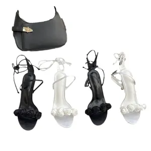 Elegante Schnürsandalen mit hohen Absätzen, Rosenstrauß und passender schwarzer Handtasche.