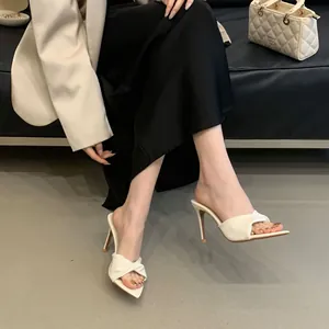 Λεπτομέρεια από λευκά mules με μυτερή μύτη, στριφτό κόμπο και λεπτό ψηλό τακούνι