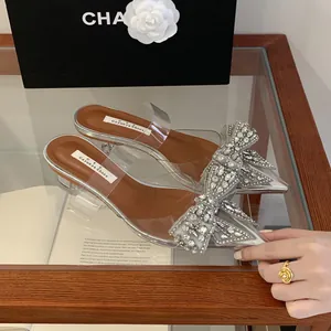 Detailansicht silberner Mules mit großer Strassschleife und durchsichtigem PVC-Band