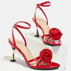 Close-up detail of red satin high heel sandals featuring a decorative silk rose