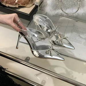 Detailed shot of silver pointed-toe stiletto heels featuring a sparkling rhinestone bow.