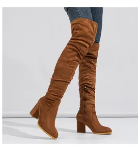 Detail view of brown suede over-the-knee boots with chunky high heels and side zipper.