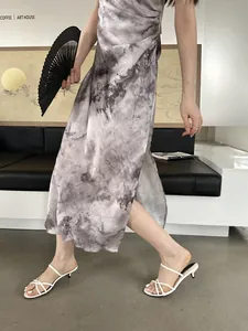 Sandales élégantes à talons aiguilles blancs portées avec une robe tie-dye en détail