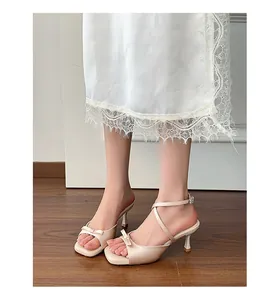 Elegant beige stiletto heel sandals featuring a butterfly bow and delicate ankle strap detail.