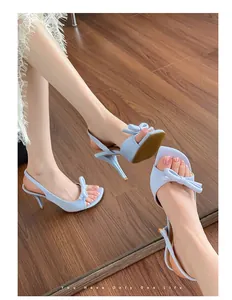 Detail view of elegant light blue French style sandals featuring a bow and thin high heels