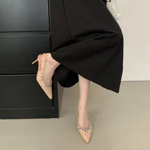 Nahaufnahme der eleganten beigen spitzen Kitten-Heels mit funkelndem Strassbesatz.