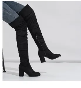Detailed side view of elegant black suede over-the-knee boots with chunky high heels.