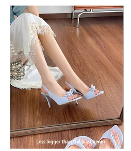 Elegant light blue slingback high heel sandals with a delicate bow detail shown on a model