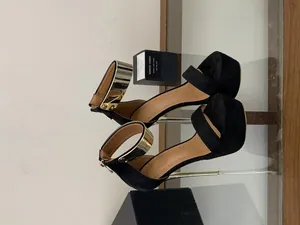 Close-up of black platform high heel sandals with gold metallic ankle straps